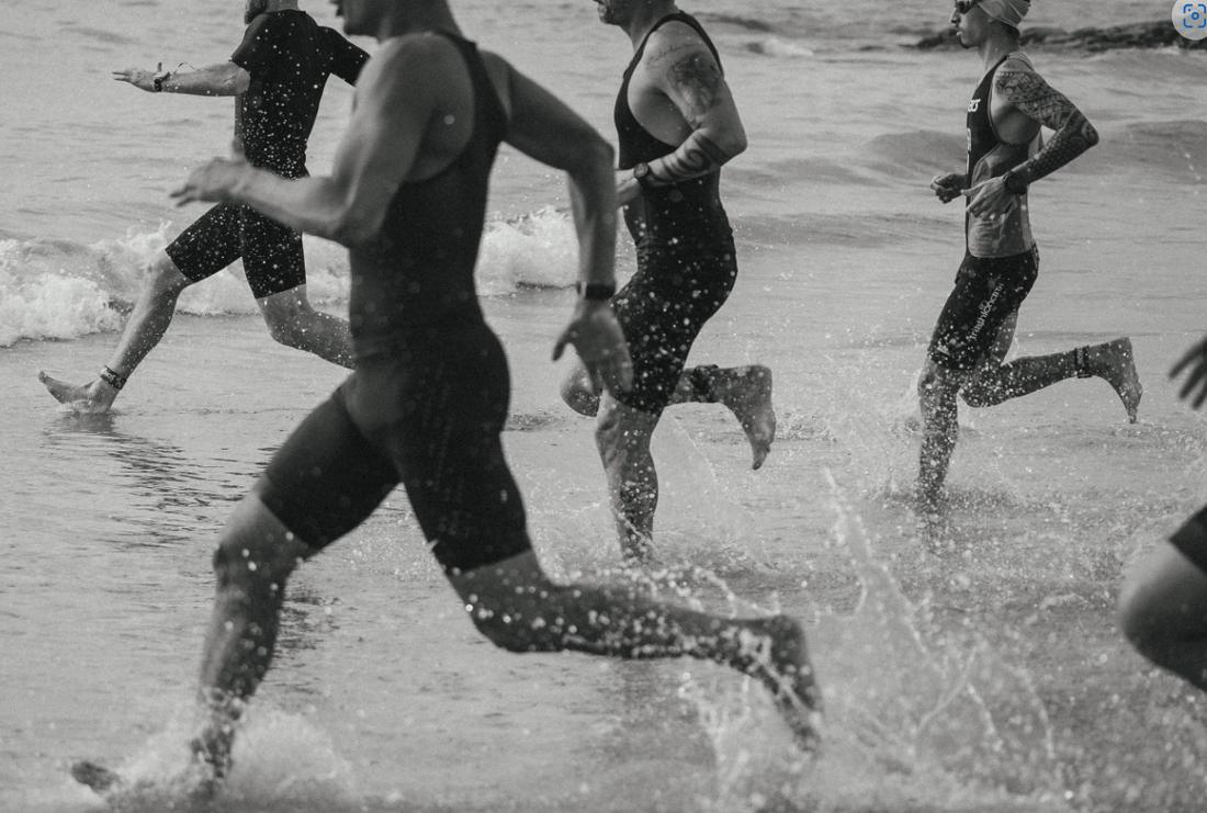 Black and white photo of people running into the sea
